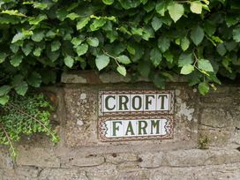 A sign labeled 'CROFT FARM' on a stone wall with greenery at Yeat Stoup Cottage in Cockermouth