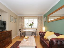 A living room with a brown leather sofa yellow cushions a wooden coffee table a small dining table with two chairs and a wooden dresser at Alway in Lifton