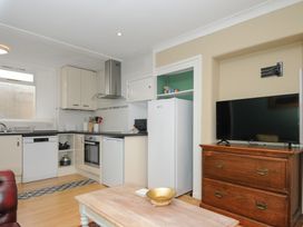 A kitchen with white cabinets dishwasher oven fridge and a wooden chest with a television at Alway Lifton