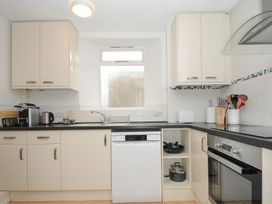 A kitchen with white cabinets a dishwasher a sink an oven a coffee machine and various utensils at Alway in Lifton