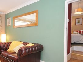 A leather sofa with cushions against a green wall with a wooden framed mirror and a lamp in a living room at Alway in Lifton