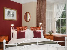 A bedroom with a white metal bed frame red and white pillows bedside tables lamps and a window with curtains at Alway in Lifton