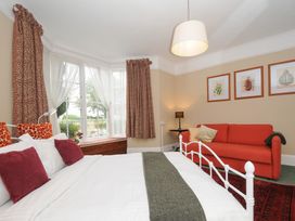 A bedroom with a bed, a red sofa, and a large window with curtains at Alway in Lifton