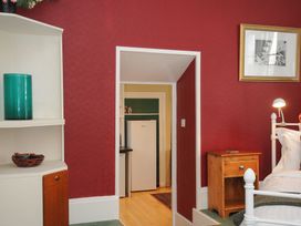 A bedroom with a white metal bed frame wooden bedside table and a doorway leading to a kitchen at Alway in Lifton