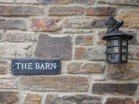 A stone wall with a black lantern and a sign that reads The Barn at The Barn in Lifton