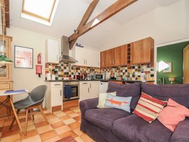 A kitchen with tiled backsplash white and wood cabinets and a purple sofa with cushions at The Barn in Lifton