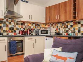 A kitchen with multicolored tile backsplash cabinets and appliances and a purple chair with pillows at The Barn Lifton