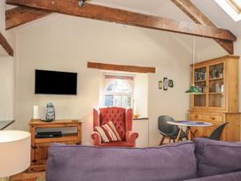 A living room with a purple sofa a red armchair a wooden cabinet and a dining table with chairs at The Barn in Lifton