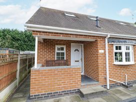 The exterior of a brick house with a small covered porch containing a wooden bench at Rooster in Stourport-On-Severn