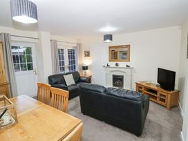 A living room with two black leather sofas a fireplace a television on a wooden stand and a wooden dining table at Rooster in Stourport-On-Severn