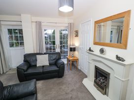 A living room with black leather sofas a fireplace a wall mirror a side table with a lamp and glass doors leading outside at Rooster in Stourport-On-Severn