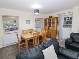 A dining area with wooden table and chairs next to a cabinet and black leather sofas at Rooster in Stourport-On-Severn