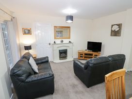 A living room with two black sofas a fireplace a television on a wooden stand and a wooden chair at Rooster in Stourport-On-Severn