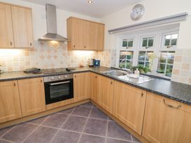 A kitchen with wooden cabinets black countertop a stove an oven a sink and a window at Rooster in Stourport-On-Severn