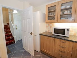A kitchen with wooden cabinets a microwave on the countertop a white refrigerator and a view of a hallway and staircase at Rooster in Stourport-On-Severn
