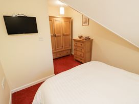 A bedroom with a bed a wall-mounted television a wooden wardrobe and chest of drawers at Rooster in Stourport-On-Severn