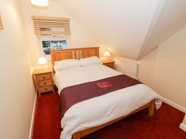 A bedroom with a double bed two bedside tables with lamps a window and red carpet at Rooster in Stourport-On-Severn