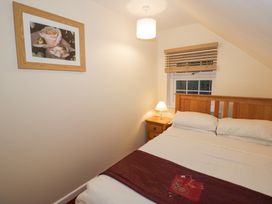 A bedroom with a wooden bed frame bedside table lamp and framed picture on the wall at Rooster in Stourport-On-Severn