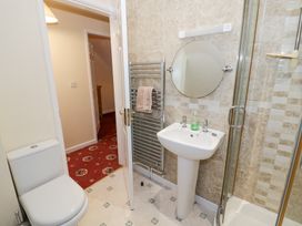 A bathroom with a toilet pedestal sink round mirror towel rack and shower at Rooster in Stourport-On-Severn