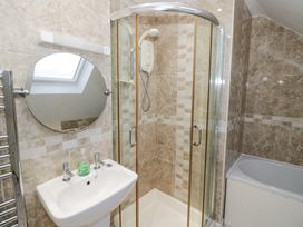 A bathroom with a shower enclosure a sink with soap and a round mirror at Rooster in Stourport-On-Severn