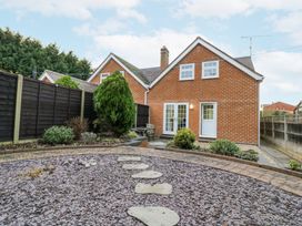 A backyard with stone pathway leading to a brick house with white doors and windows at Rooster in Stourport-On-Severn