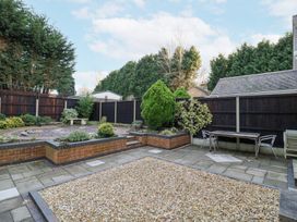 A backyard with a gravel area a paved patio raised flower beds and a table with chairs at Rooster in Stourport-On-Severn