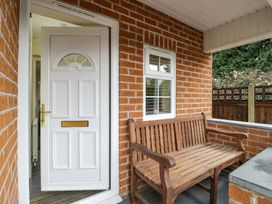 A porch area with a white door and a wooden bench outside a brick house at Hen and Chickens in Stourport-On-Severn