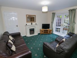 A living room with two brown leather sofas a fireplace a wooden TV stand with a TV and glass doors with green curtains at Hen and Chickens in Stourport-On-Severn
