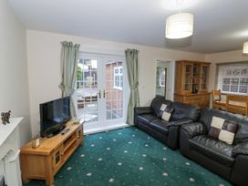 A living room with leather sofas wooden TV stand and a dining area at Hen and Chickens in Stourport-On-Severn