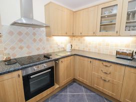 A kitchen with wooden cabinets a stove oven kettle toaster and tiled backsplash at Hen and Chickens in Stourport-On-Severn