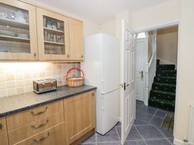A kitchen with wooden cabinets a toaster a basket a white fridge and stairs visible through an open door at Hen and Chickens in Stourport-On-Severn