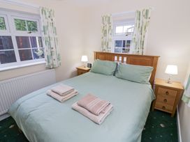 A bedroom with a double bed green bedding wooden headboard two bedside tables with lamps and folded towels at Hen and Chickens in Stourport-On-Severn