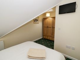 A bedroom with a sloped ceiling a bed with towels a wooden wardrobe a wall-mounted TV and a hanging lamp at Hen and Chickens in Stourport-On-Severn