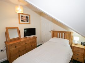 A bedroom with a single bed a wooden dresser with a mirror and a television a wooden nightstand with a lamp and clock at Hen and Chickens in Stourport-On-Severn