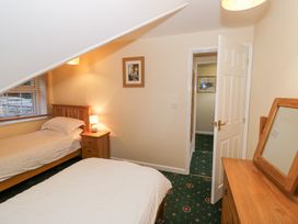 A bedroom with two single beds a wooden nightstand with a lamp a dresser with a mirror and an open door at Hen and Chickens in Stourport-On-Severn