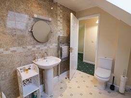 A bathroom with a pedestal sink mirror towel rack toilet and open door showing a hallway at Hen and Chickens in Stourport-On-Severn