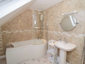 A bathroom with a bathtub shower combination a sink with a mirror and a small white shelving unit at Hen and Chickens in Stourport-On-Severn