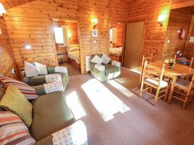 A wooden living room with green armchairs a sofa and a dining table at Goldcrest in Withern near Alford