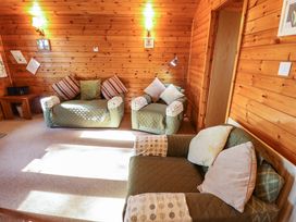 A sitting room with wooden walls and multiple armchairs with cushions at Goldcrest in Withern near Alford