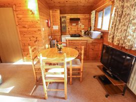 A kitchen and dining area with a wooden table and chairs television and appliances at Goldcrest in Withern near Alford