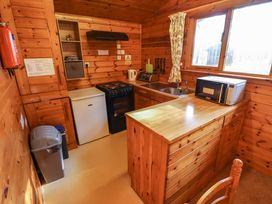 A kitchen with wooden cabinets a stove a refrigerator a microwave a sink and a window at Goldcrest in Withern near Alford