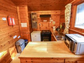 A kitchen with wooden walls a stove microwave sink kettle toaster and window at Goldcrest in Withern near Alford