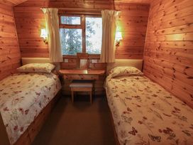 A bedroom with two single beds a wooden dressing table and a window at Goldcrest Withern near Alford