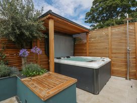 A hot tub and wooden seating area in the garden at Hilltop Cottage Conwy