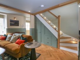 A living room with a sofa and a staircase at Hilltop Cottage in Conwy