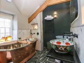 A bathroom with a copper bathtub and decorative sinks at Hilltop Cottage in Conwy