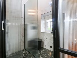 A bathroom with a shower, toilet, and window at Hilltop Cottage in Conwy