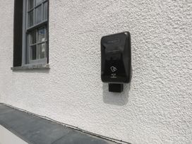 An electric vehicle charger mounted on an exterior wall at Hilltop Cottage in Conwy