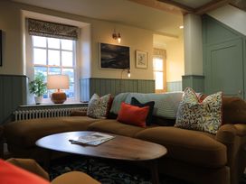 A living room with a sofa, table, and lamp at Hilltop Cottage in Conwy