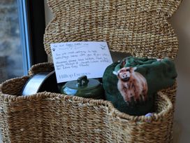 A dog basket with a note, a bowl, and a blanket with a sheep pattern at Hilltop Cottage in Conwy